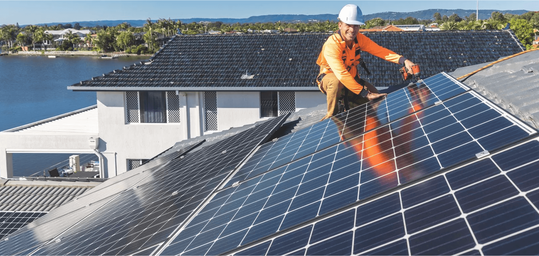 Smiling man working on solar panels on a roof